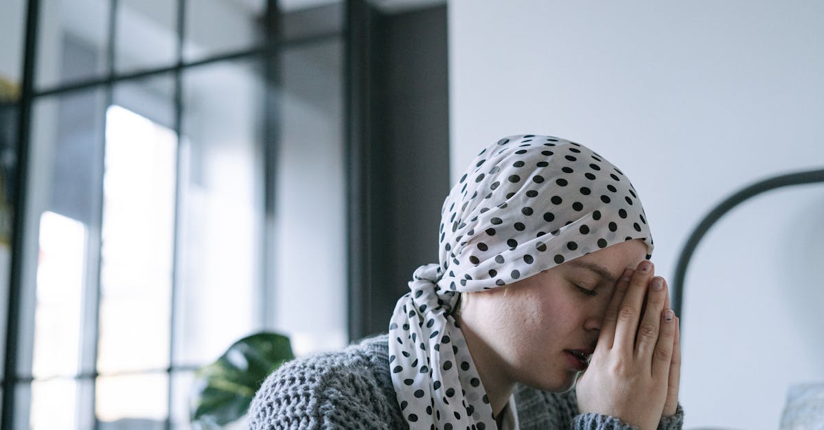A cancer patient wearing a polka dot headscarf sits quietly, illustrating contemplation and the emotional journey during treatment, relevant to discussions on therapies like red light therapy.