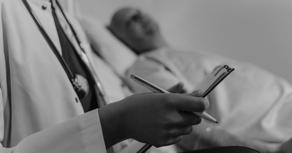 Gydytojas su planšete ir rašikliu, sėdintis šalia paciento medicinos įstaigoje, simbolizuoja emocinę paramą ir konsultacijas išgyvenusiems vėžį.