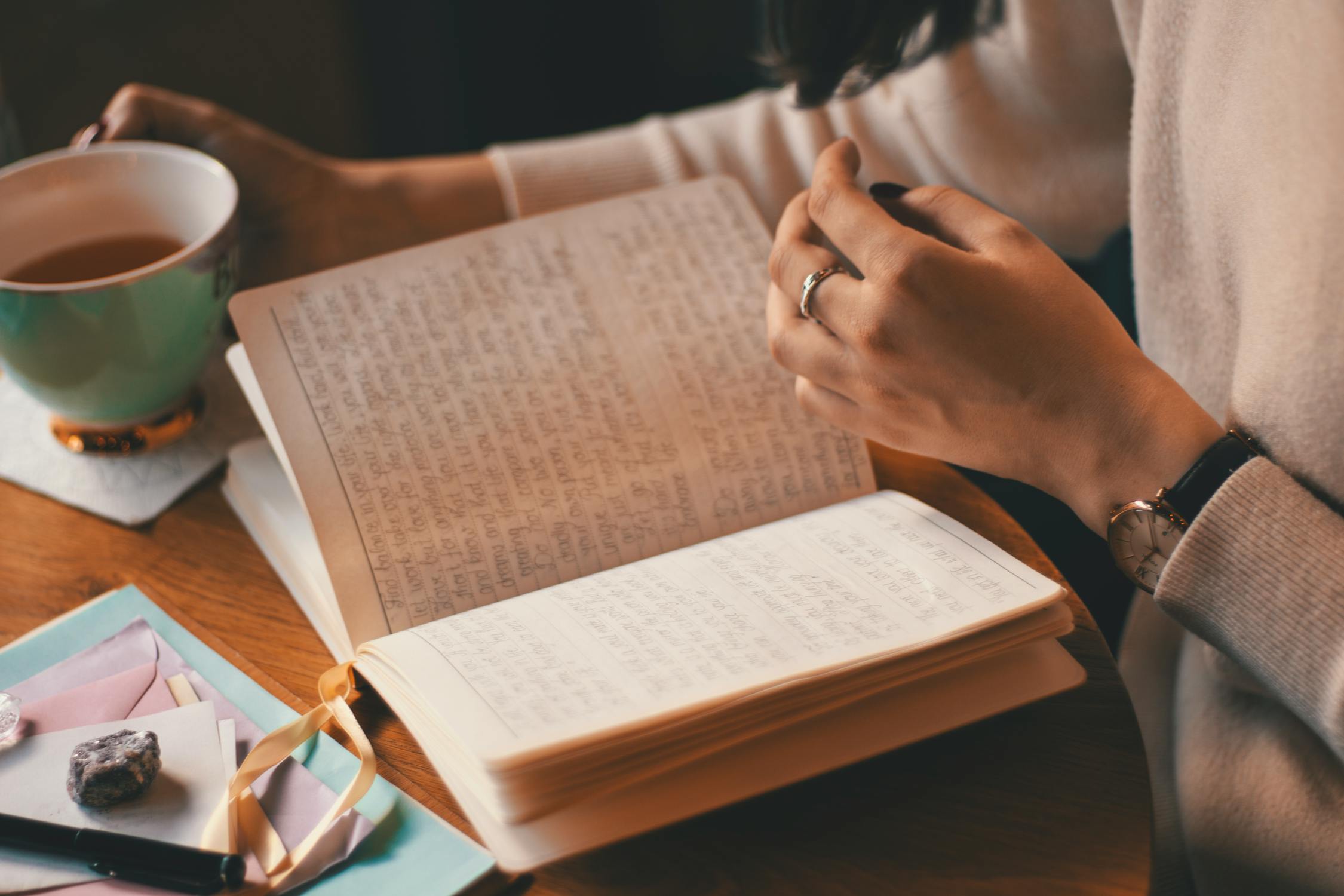 Eine Person, die mit einer Tasse Tee in der Hand in ein Tagebuch schreibt, symbolisiert den therapeutischen Nutzen des Tagebuchschreibens für Krebsüberlebende und -patienten.