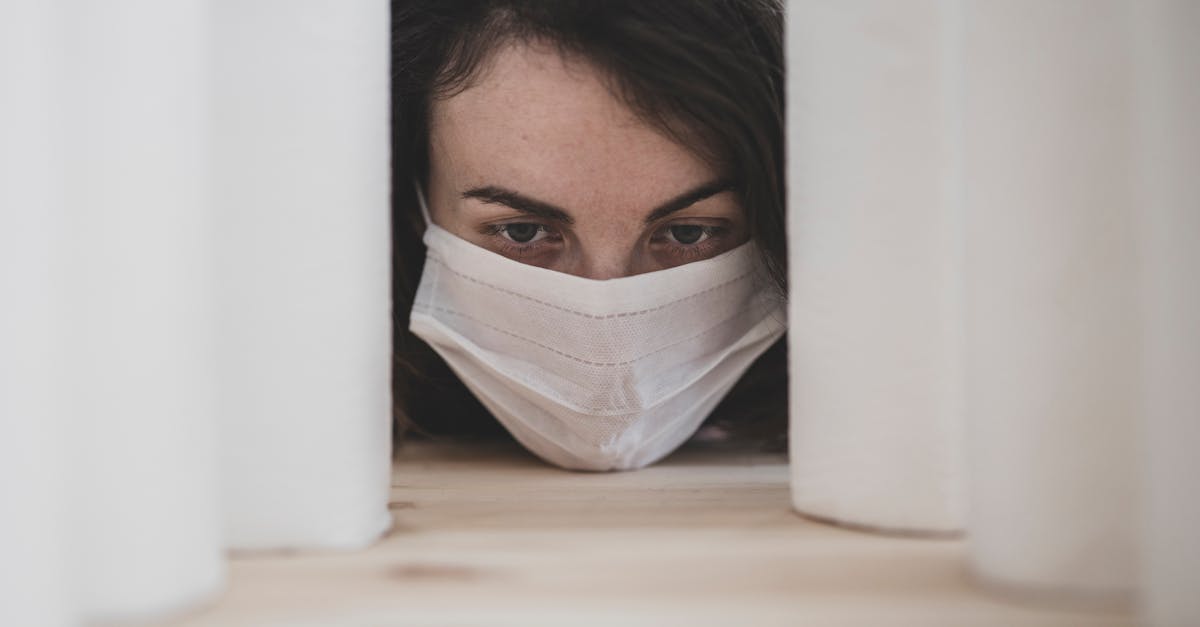 Osoba koja nosi kiruršku masku viri između velikih smotaka medicinskih potrepština, naglašavajući važnost osnovnih stvari tijekom boravka u bolnici.