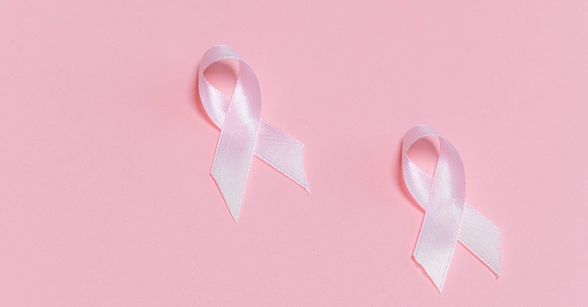 Dos lazos rosas de concienciación que simbolizan el apoyo al cáncer sobre un fondo rosa.