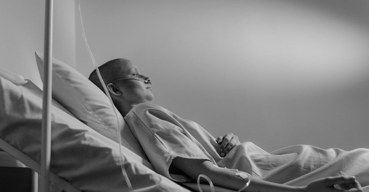A person in a hospital bed connected to an IV, symbolizing the loneliness and isolation often experienced by cancer survivors during recovery.