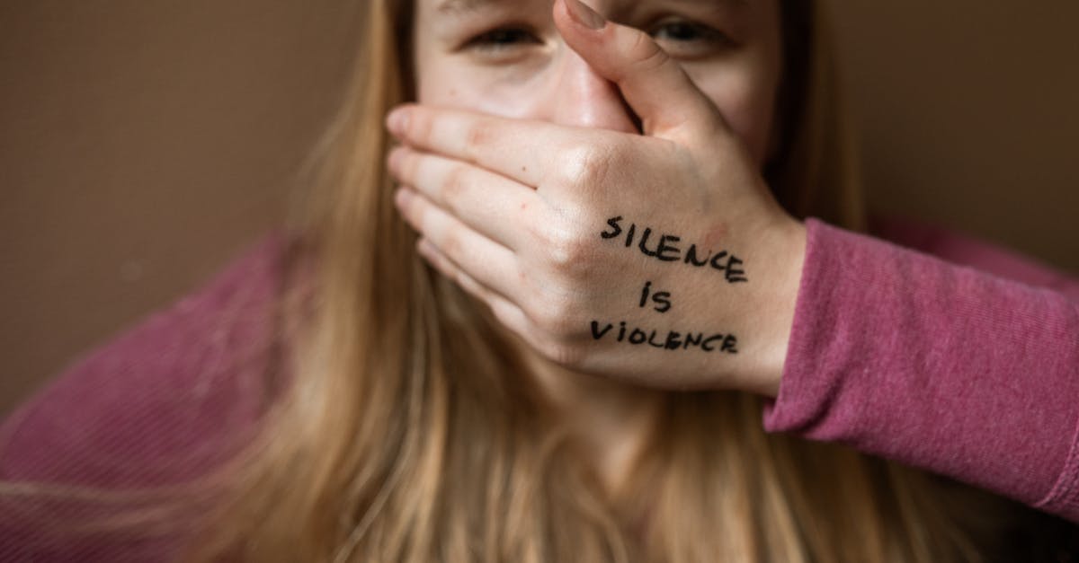 A woman covering her mouth with her hand, which has "Silence is Violence" written on it, symbolizing the importance of speaking up for health issues like prostate awareness.