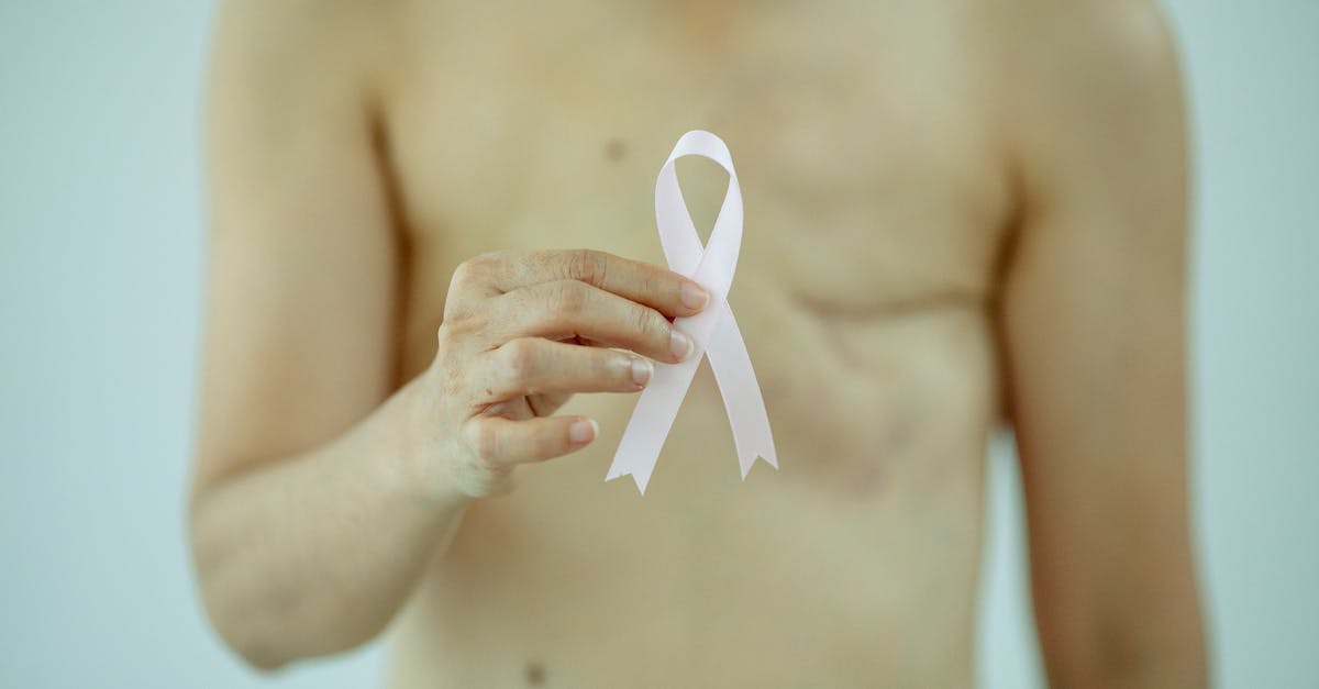O persoană ține în mână o panglică albă de conștientizare, simbolizând conștientizarea cancerului și sprijinul pentru cei afectați de metastazele cancerului.