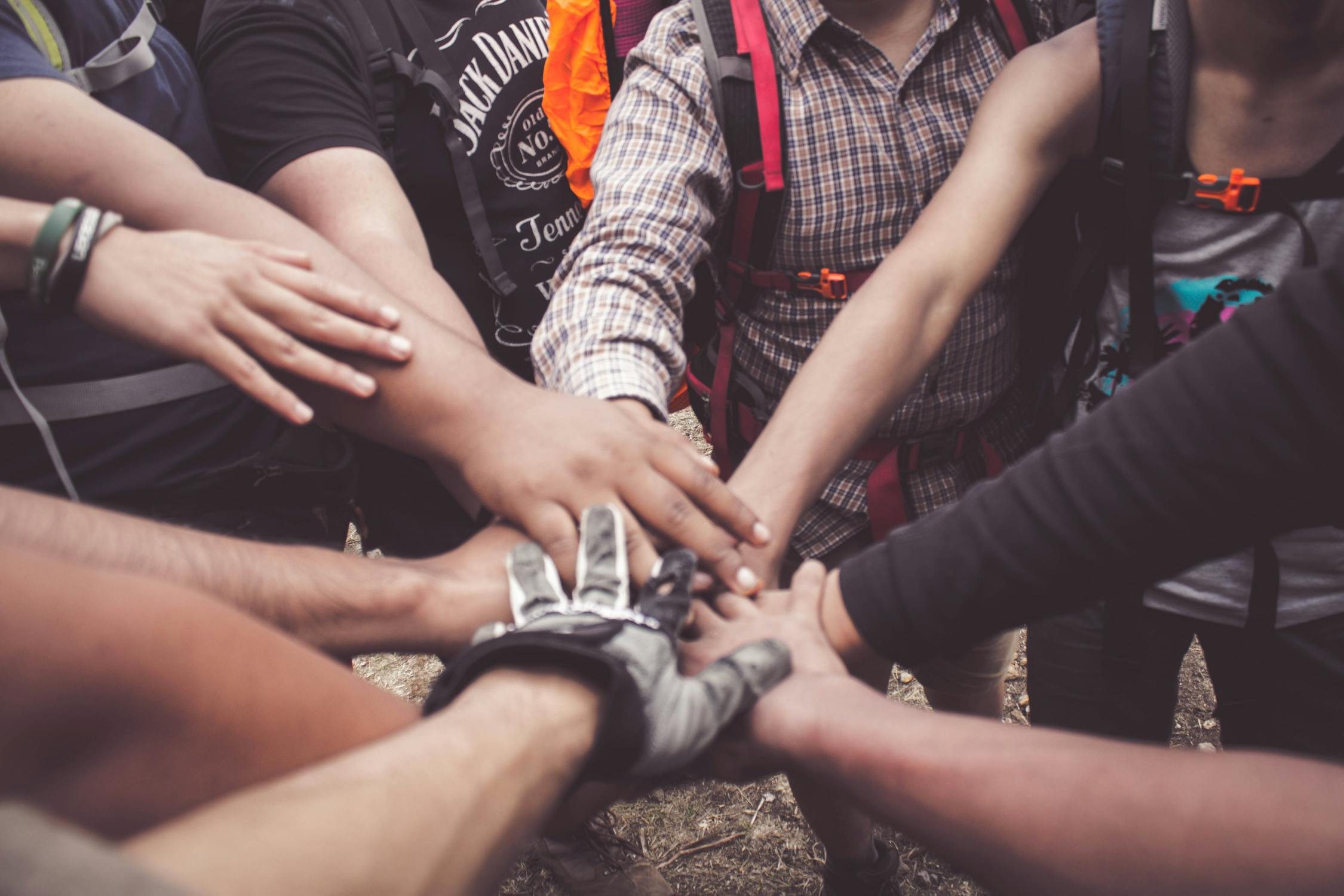 Group of people joining hands in solidarity, symbolizing support and community for cancer survivors thriving after treatment.